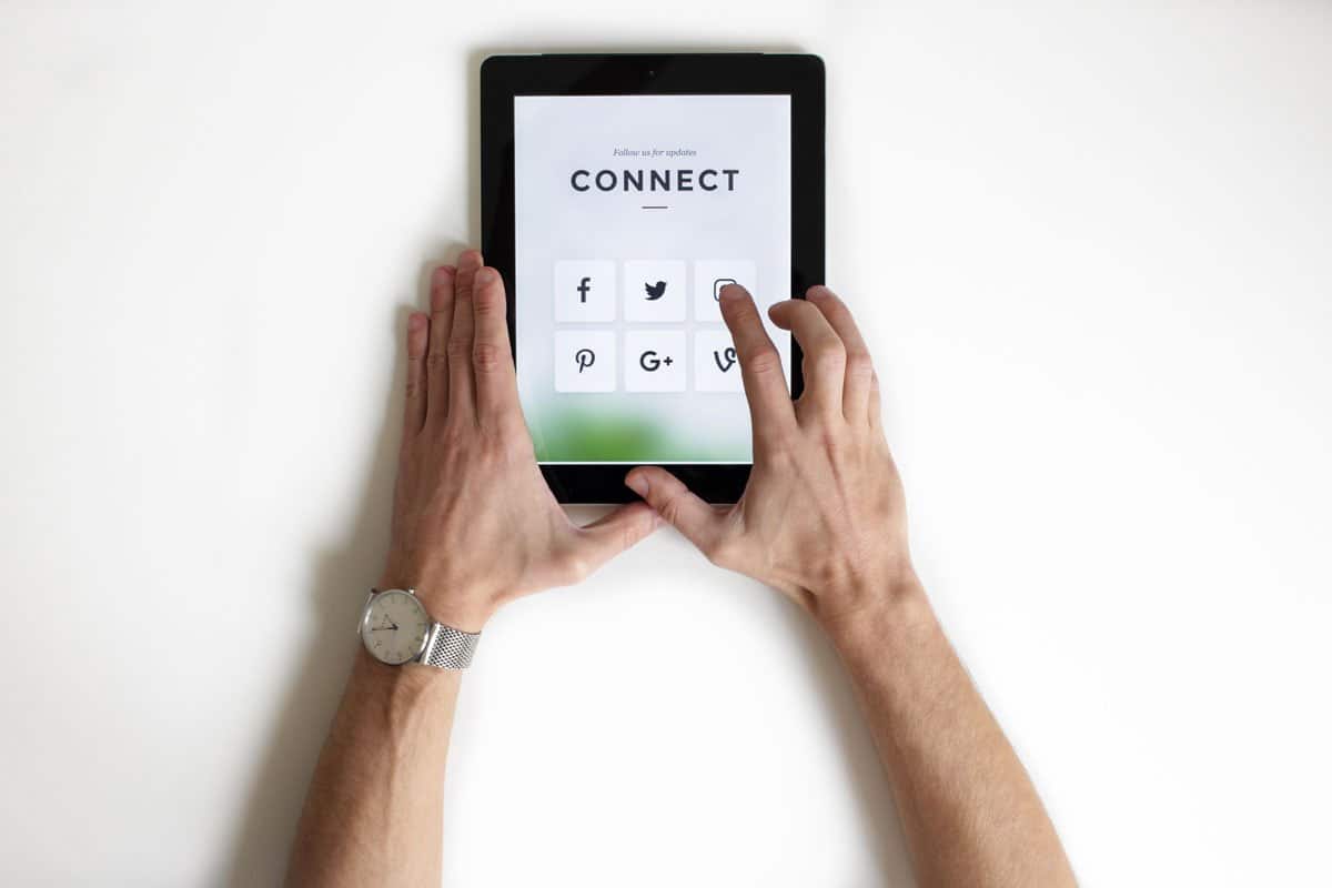 A man using a tablet that's displaying an invitation to connect on social media.