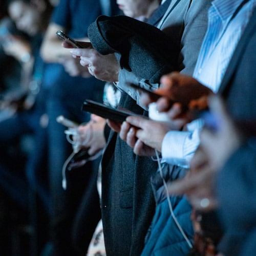 Businesspeople looking at their smartphones during an event.