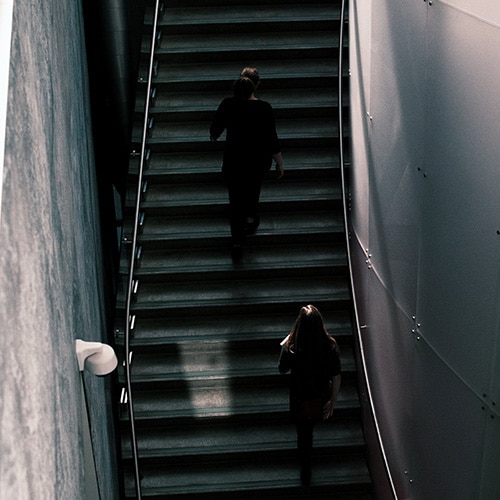 Two women climbing a set of stairs at the Art Gallery of Alberta