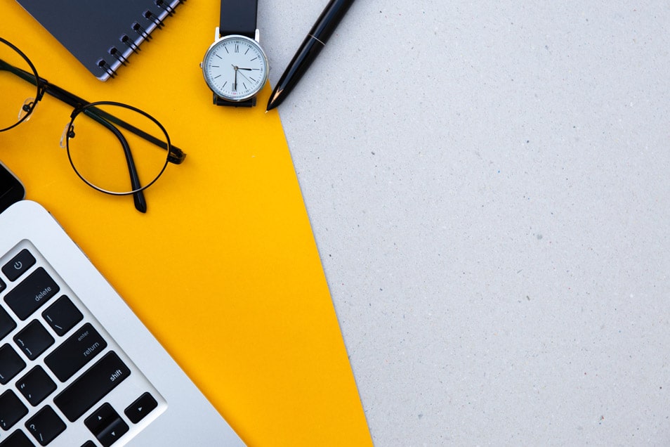 A laptop on a desk with a bright yellow background